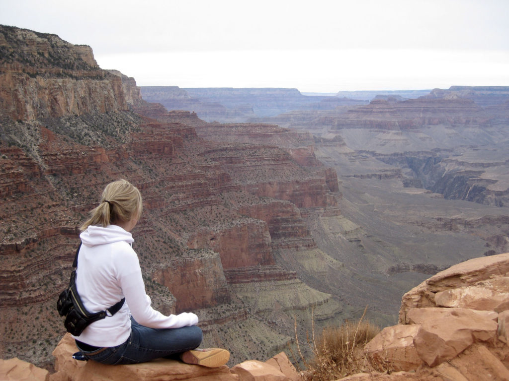 woman sitting atop grand canyon